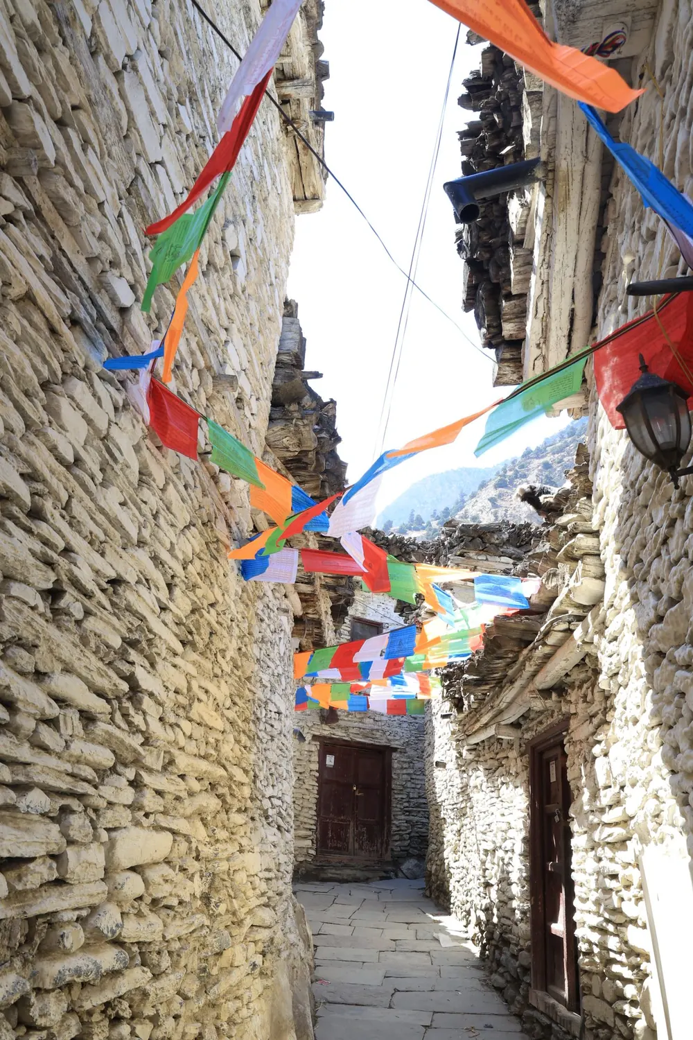 Prayer flags strung across a stone alley in Mustang